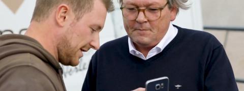 Mario Weidemann und Peter Hagedorn und schauen auf ein Smartphone.